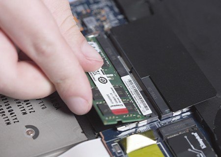 Mano instalando un módulo de memoria RAM en una notebook